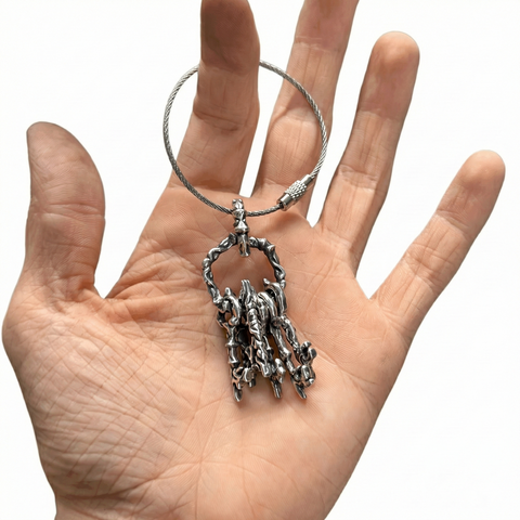 Hand holding a silver Keychain with a detailed pendant against a white background