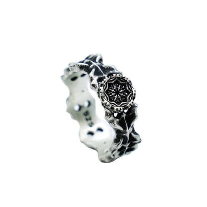 Silver ring with intricate design on a light gray background