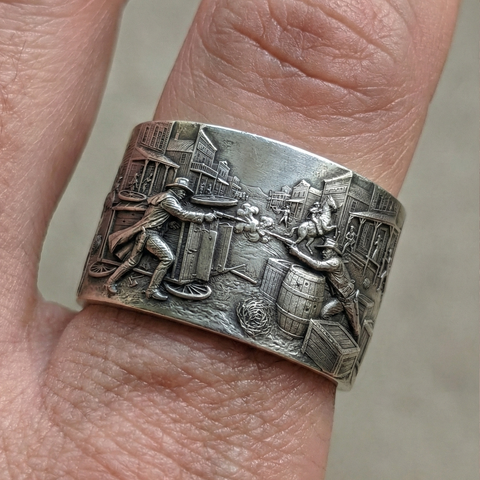 Silver ring with detailed design on a finger